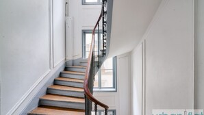 Un escalier avec des marches en bois et une rampe métallique, menant à l’étage supérieur.