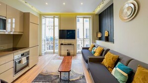 Ein modernes Wohnzimmer mit einer Couch, einem Couchtisch, einem Fernseher und einem Balkon mit Blick.