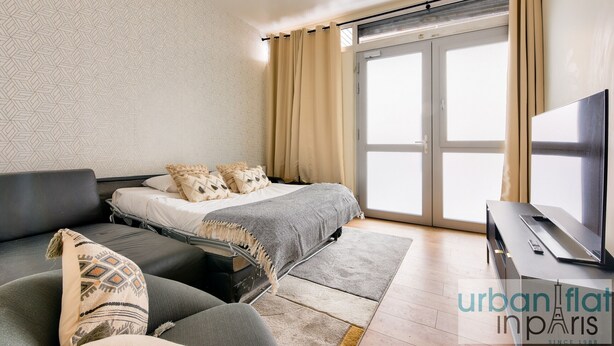 A modern bedroom with a bed, a sofa, and a TV. - Urban Flat 159 - Charming 3BDR Flat in Paris (París)