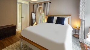 A neatly arranged bedroom with a large bed, a bedside table with a lamp, a dresser, and patterned rugs. - Host & Stay | River View Cottage (Barnard Castle)