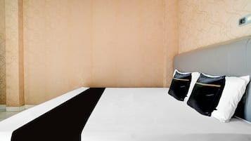 A hotel room with a bed, two pillows, a headboard, and patterned wallpaper.