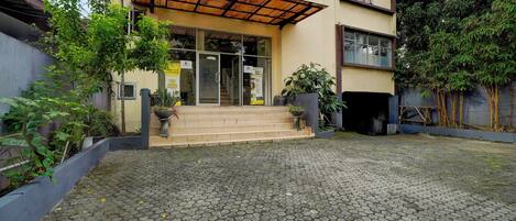 A building with a tiled entrance, potted plants, and a staircase leading to the entrance.