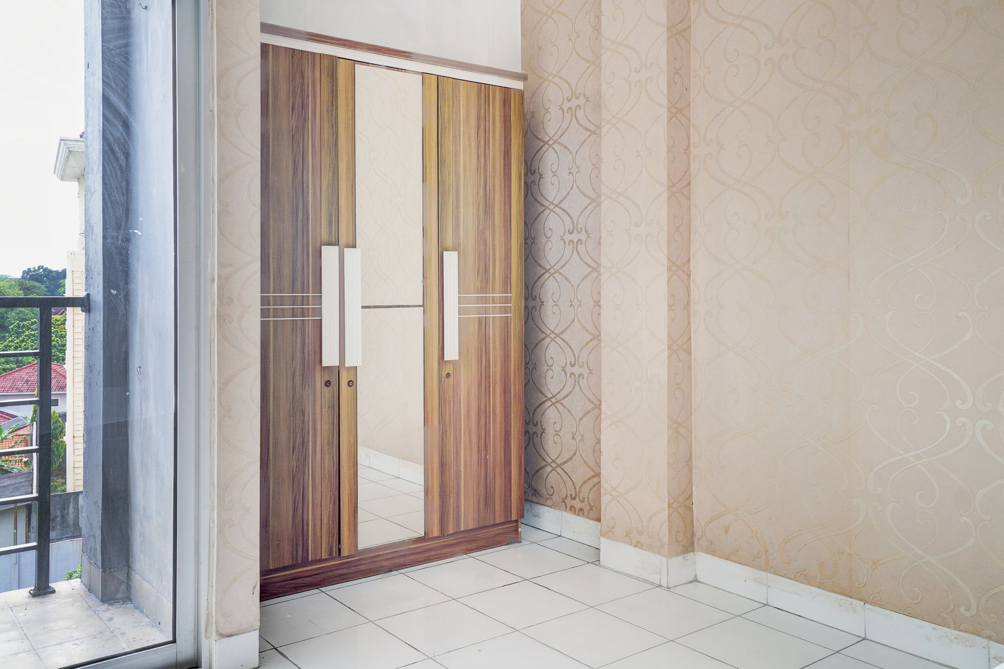 A room with a sliding wooden door, patterned wallpaper, and a tiled floor.