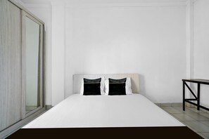 A minimalist bedroom with a large bed, a nightstand, and a sliding door. - OYO 92723 Sultan Residence Syariah (Jakarta)