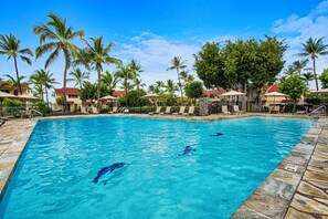 A swimming pool with lounge chairs and palm trees. - Keauhou Kona Surf & Racquet 1104: Ocean Views, Resort Amenities & Prime Location (Kailua Kona)