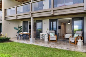 A two-story building with a covered outdoor seating area, a dining table, and chairs. - Keauhou Kona Surf & Racquet 1104: Ocean Views, Resort Amenities & Prime Location (Kailua Kona)