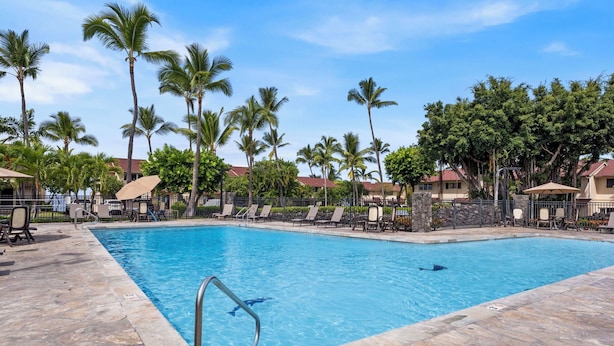 A swimming pool with lounge chairs and palm trees. - Keauhou Kona Surf & Racquet 1104: Ocean Views, Resort Amenities & Prime Location (Kailua Kona)