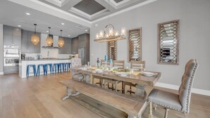 Une cuisine moderne dotée d’un îlot central, de tabourets de bar et de luminaires suspendus.
