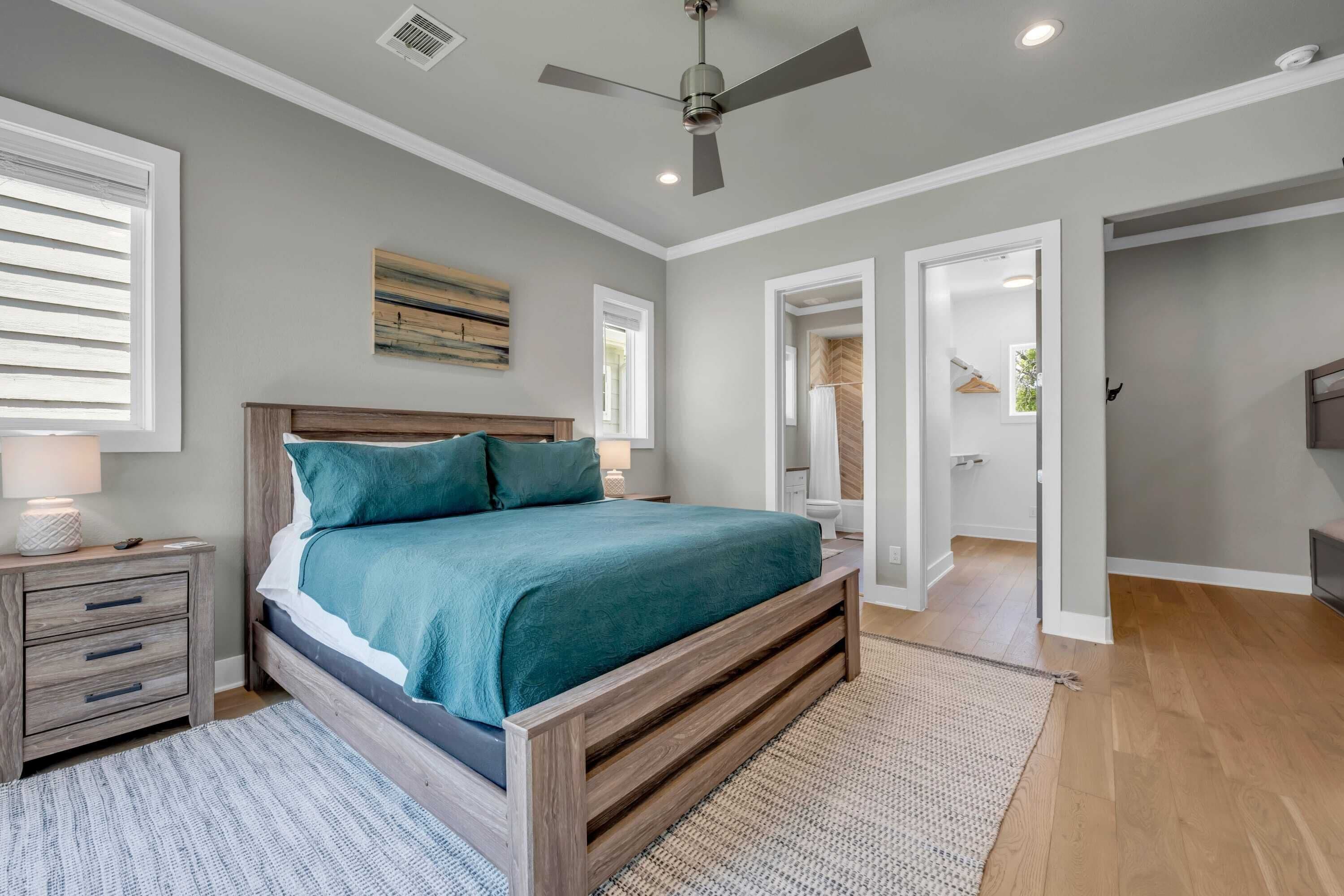 A bedroom with a wooden bed, a ceiling fan, and a view to the bathroom.