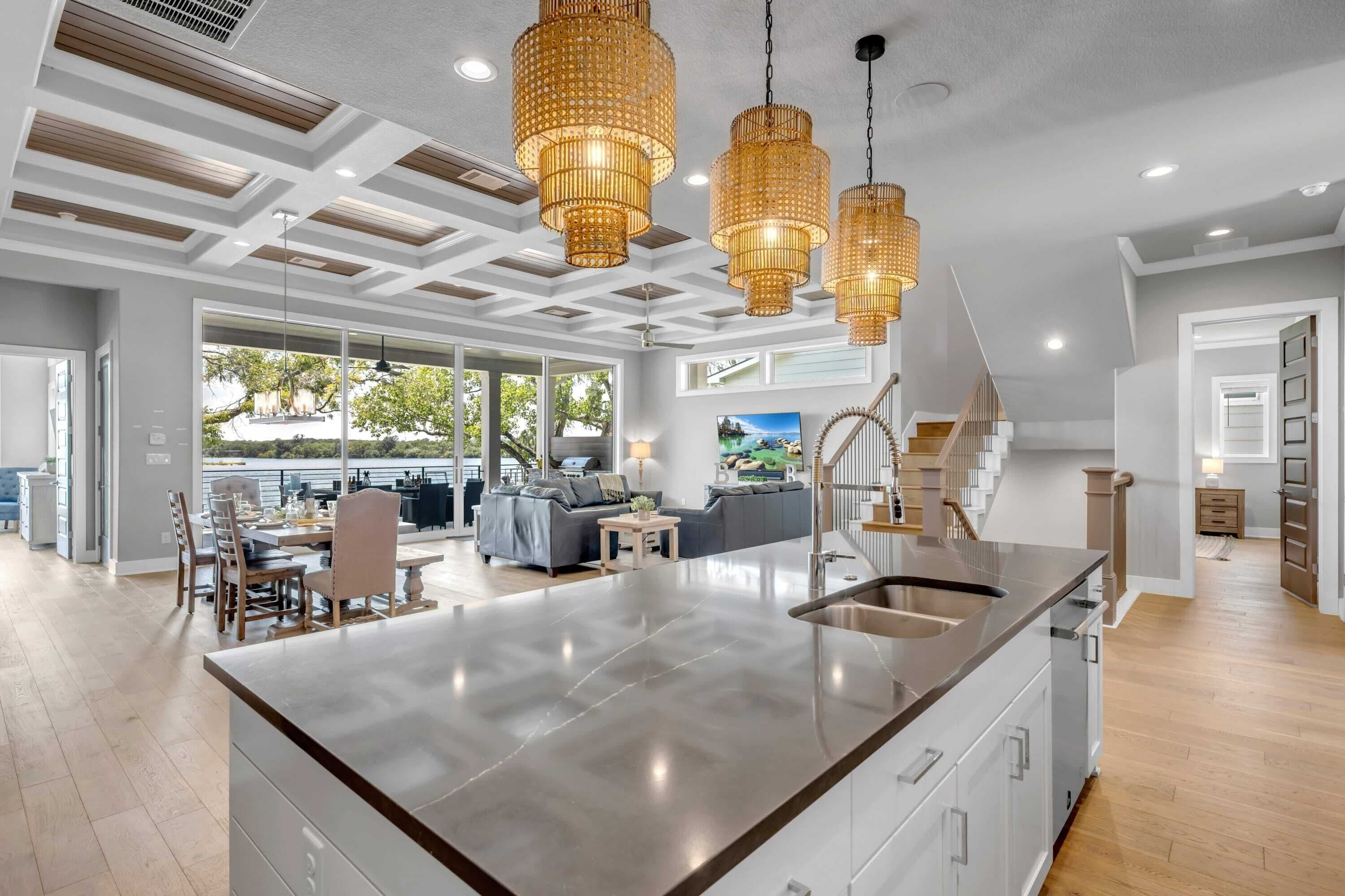 A modern kitchen with a large island, pendant lights, and a view to the outdoors.