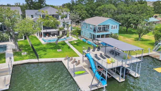 Une propriété située au bord de l’eau, dotée d’une piscine, d’un quai et d’une maison bleue.