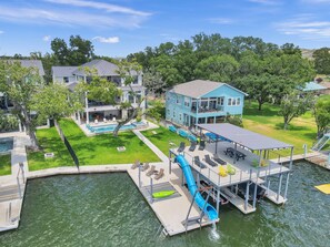 A waterfront property with a swimming pool, a dock, and a blue house. - Rolling Waves Haven | Concierge Services Available (Kingsland)
