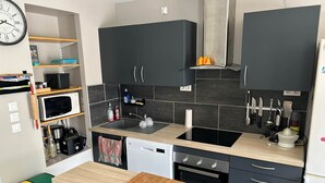 A modern kitchen with dark cabinets, a wooden countertop, a built-in microwave, a sink, and a stove.