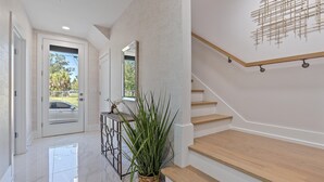 A modern interior with a staircase, a potted plant, and a view of the outside. - Uptown Luxury On Audubon 4 Bedroom Townhouse by RedAwning (Sarasota)
