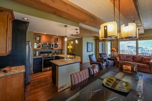 Une cuisine spacieuse dotée de plans de travail en granit, d’armoires en bois et d’un grand îlot central. On y trouve également un coin repas avec une table en verre et des chaises en cuir.