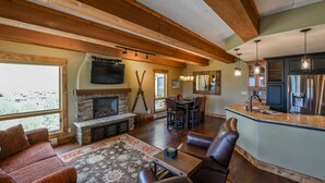 A spacious living room with a fireplace, leather seating, and a large window.