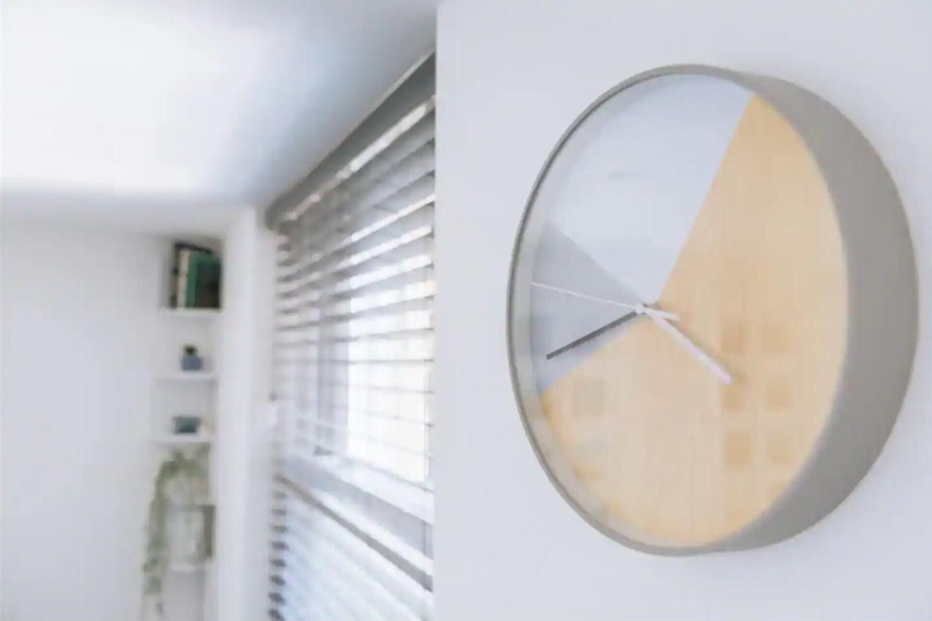 Un interno moderno con orologio a parete e una finestra con persiane.