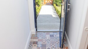 A hallway with patterned tiles leading to a wooden gate. - An Teachain (Adamstown)