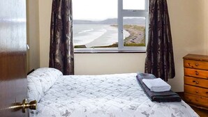 Un dormitorio con cama, ventana con cortinas y cómoda de madera.