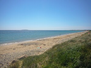 A beach with clear skies, calm waters, and a grassy area. - Tra Gheal (Kilmore)