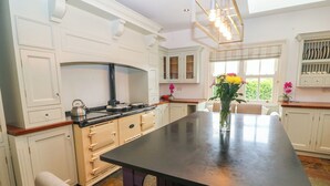 Een moderne keuken met witte kasten, een groot eiland en een eethoek met stoelen.