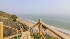 A wooden staircase leading down to a beach with a clear view of the ocean. - Beach House (Courtown)