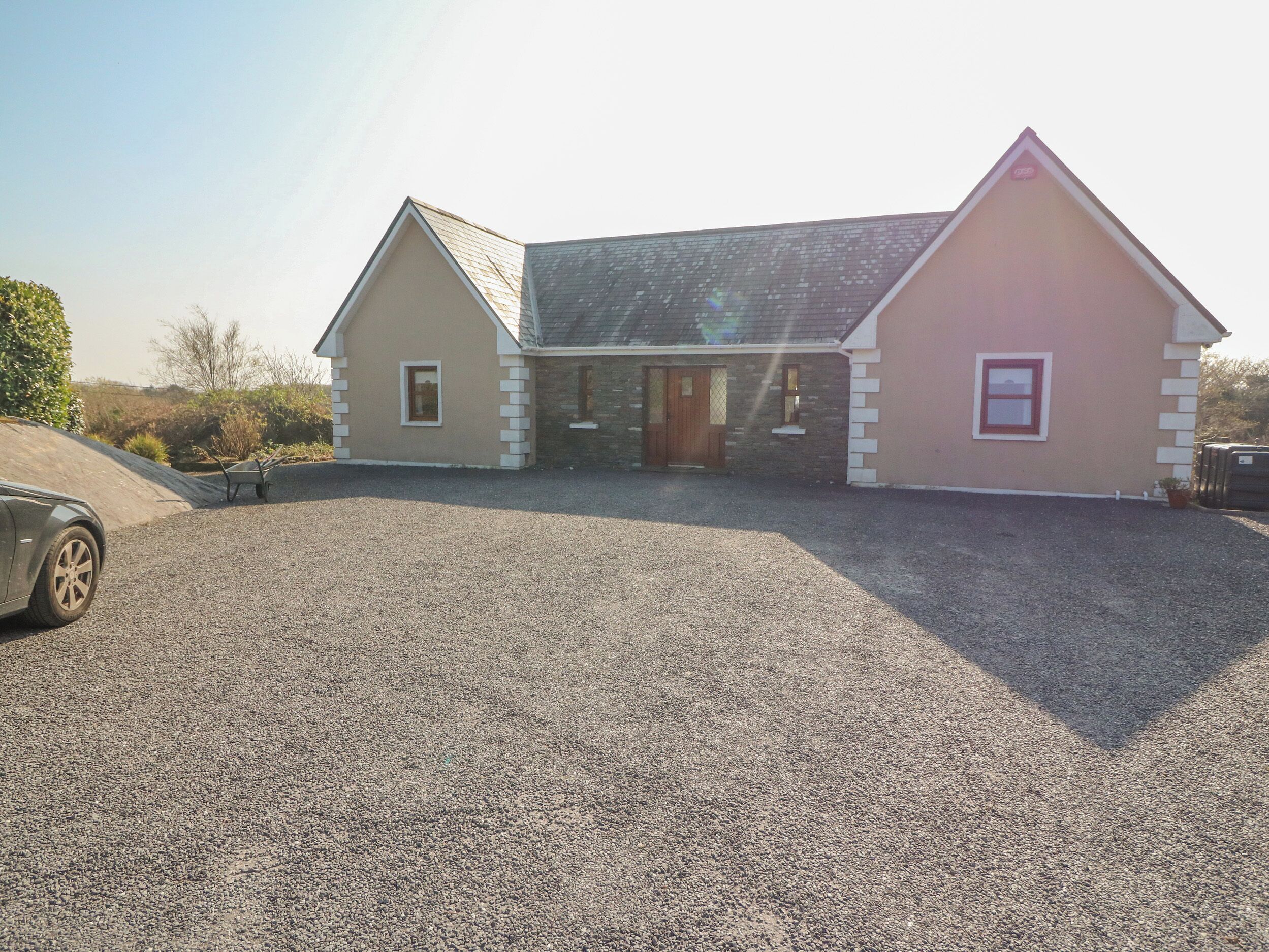 A two-story building with a gravel driveway and a parked car.