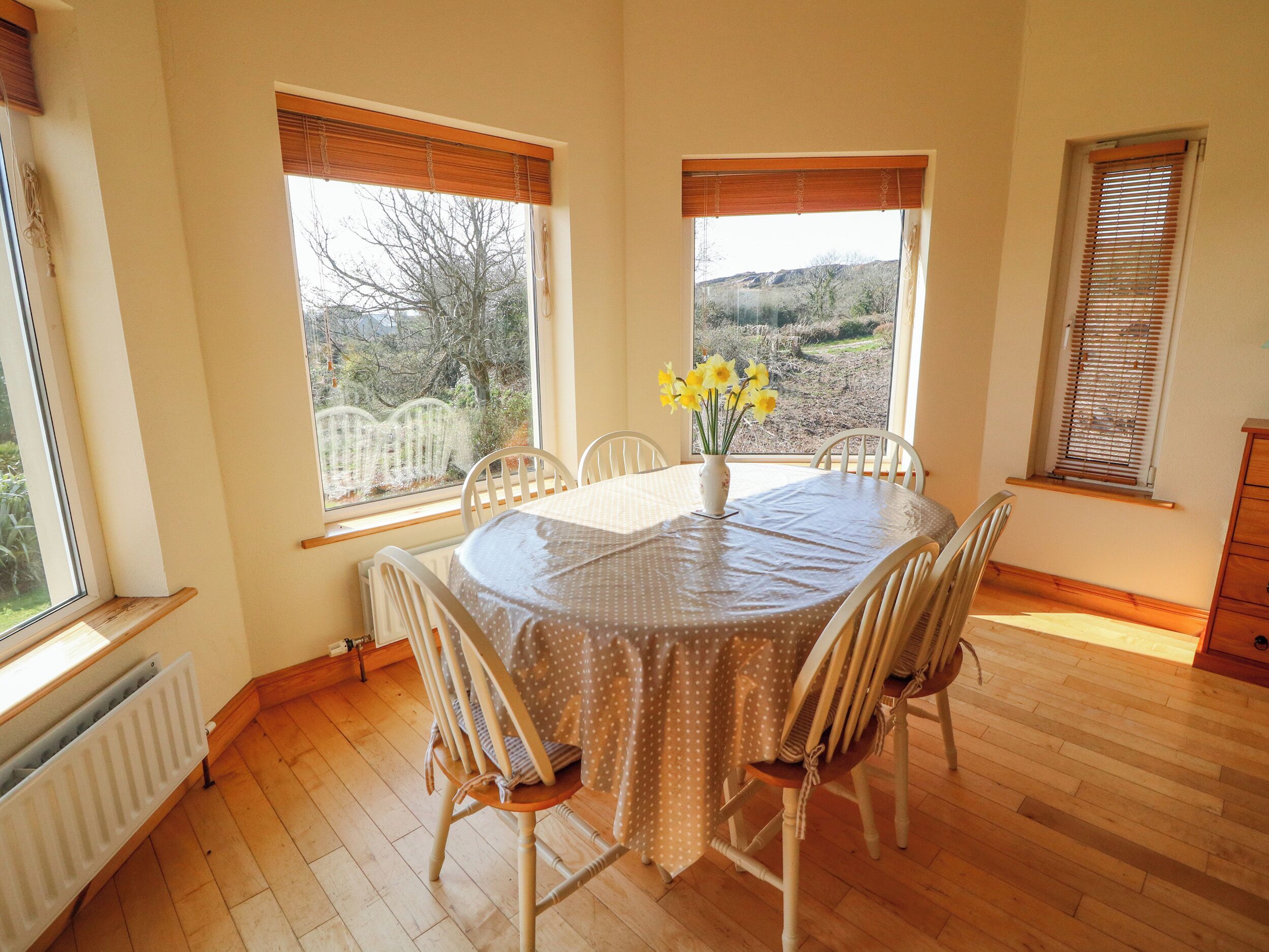 A dining area with a round table, chairs, and a vase of flowers.