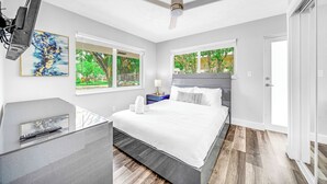 A modern bedroom with a bed, bedside tables, a ceiling fan, and large windows. - Victoria Park Gem! 1 Mile To Beach & Las Olas! (Fort Lauderdale)