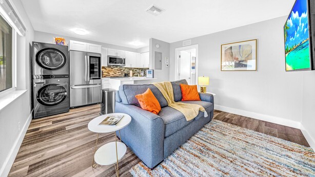 A modern living room with a grey sofa, a coffee table, and a patterned rug. - Victoria Park Getaway! 1 Mile to Beach & Las Olas! (Fort Lauderdale)