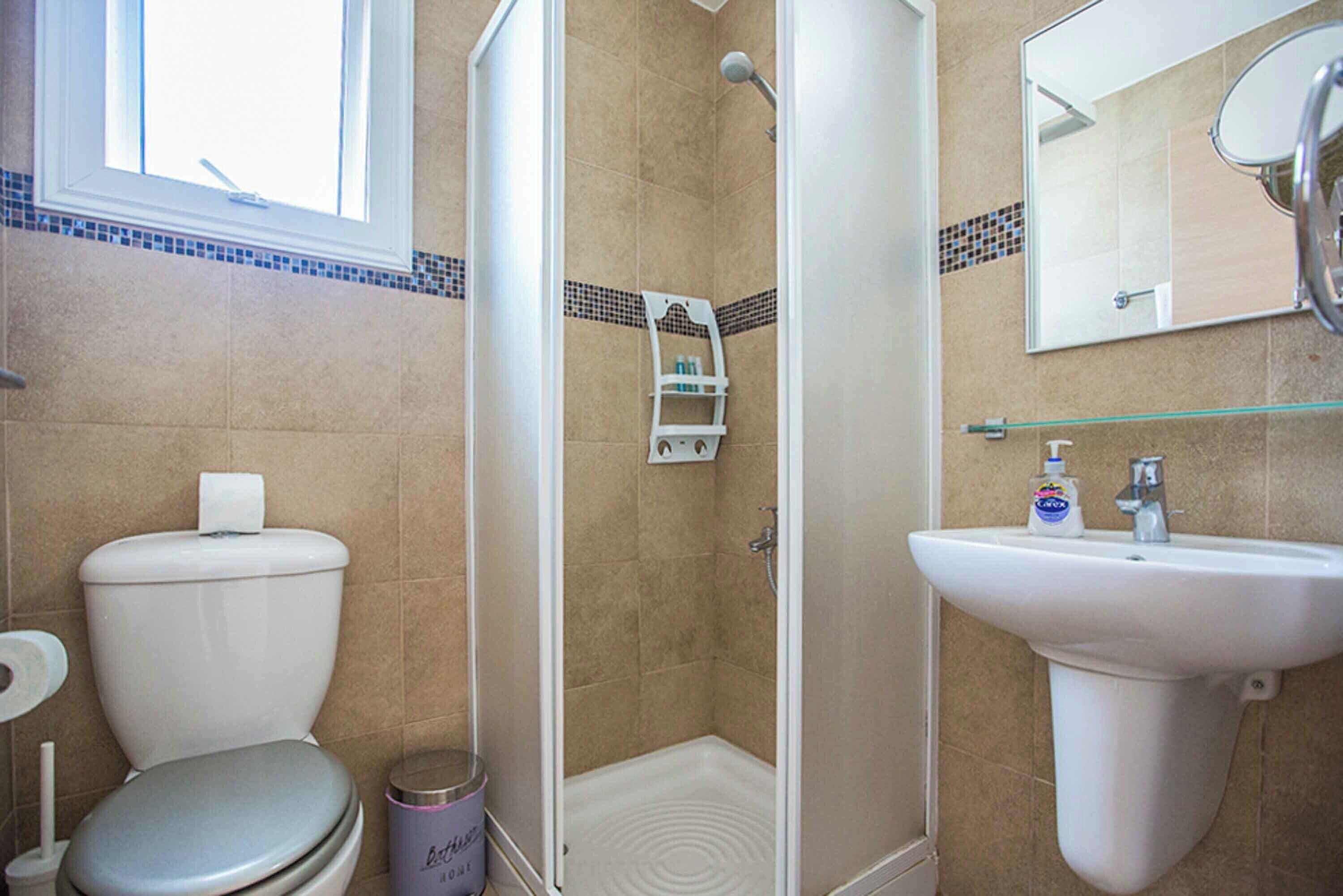 Une salle de bain équipée de toilettes, d’une douche, d’un lavabo et d’un miroir.
