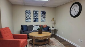 Una sala de estar con un sofá, dos sillones, una mesa de centro y un reloj de pared.