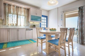 A modern kitchen with light wood cabinets, a built-in oven, and a large window with curtains.