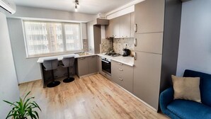 A compact kitchen with a dining area, a blue sofa, and a potted plant.
