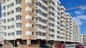 A multi-story residential building with a modern architectural design, featuring a series of balconies and air conditioning units.