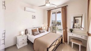 Un dormitorio con cama, mesita de noche, cómoda y ventilador de techo.