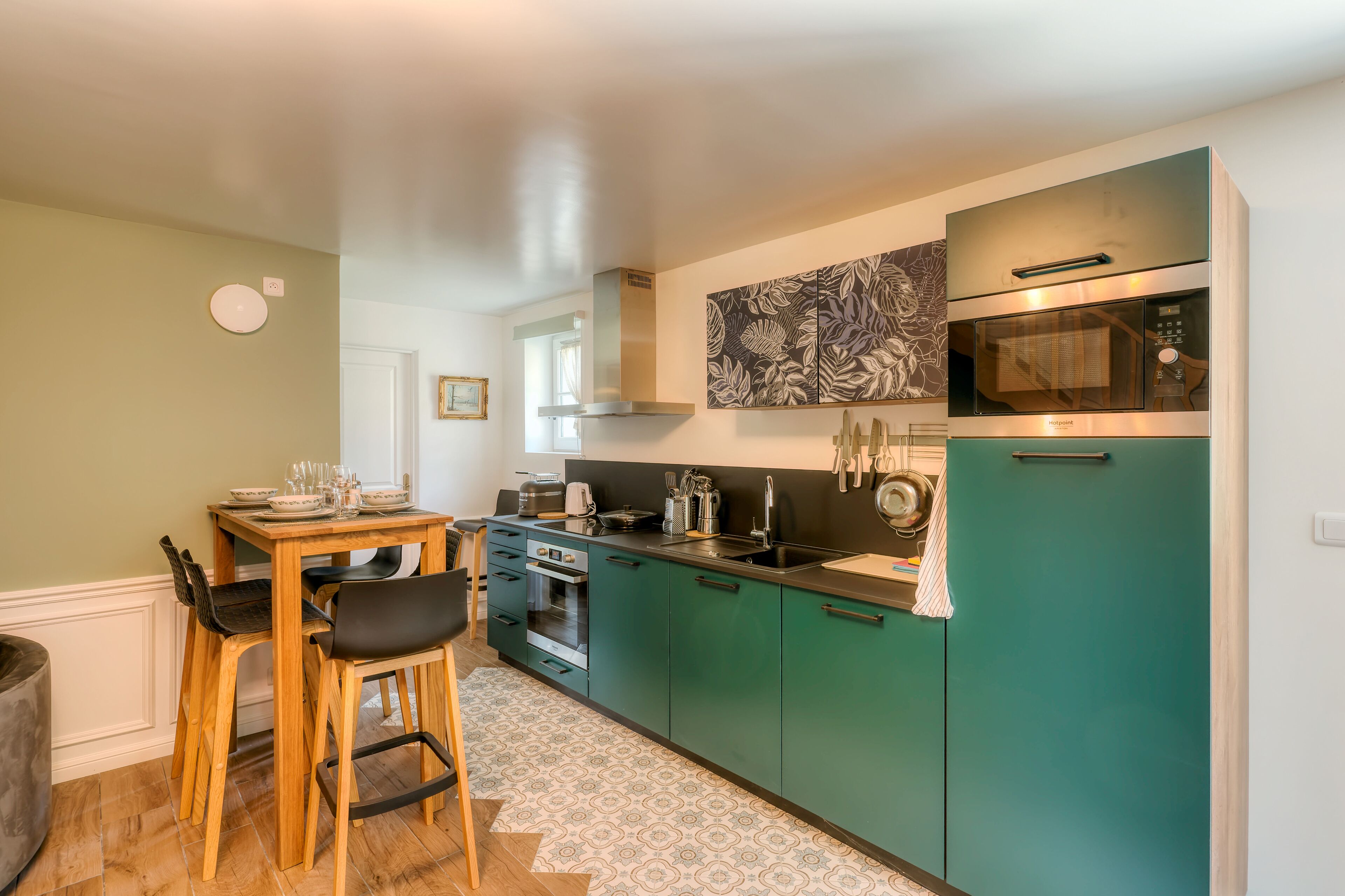 Een moderne keuken met blauwgroene kastjes, een oven van roestvrij staal en een magnetron.