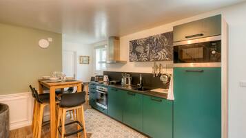 Een moderne keuken met blauwgroene kastjes, een oven van roestvrij staal en een magnetron.