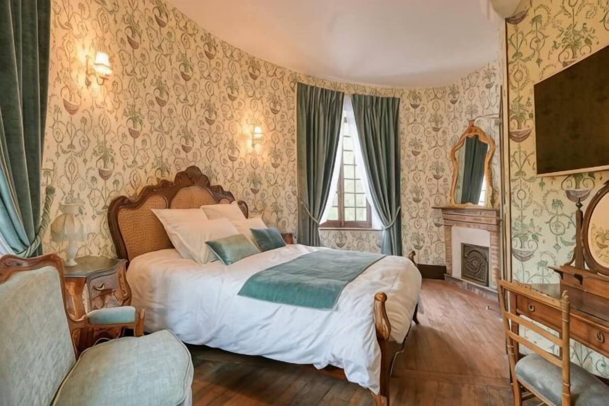 Une chambre à coucher avec un grand lit, une cheminée et un miroir au mur.