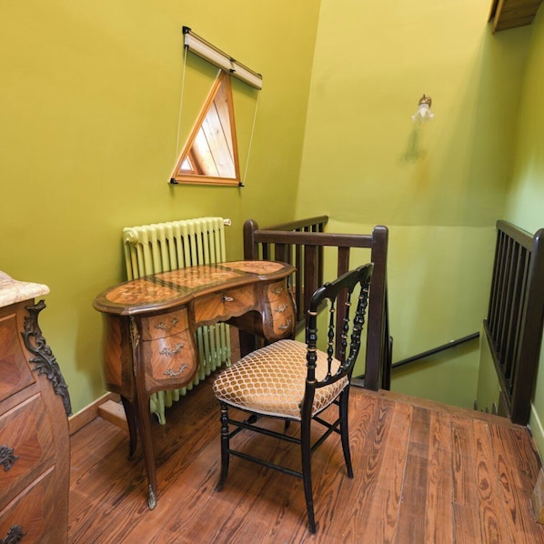 Una mesa de comedor de madera con una silla, un radiador y una ventana con cortina.