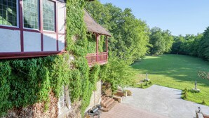 Een traditioneel huis met een balkon, een bestraat terras en een verzorgd gazon.