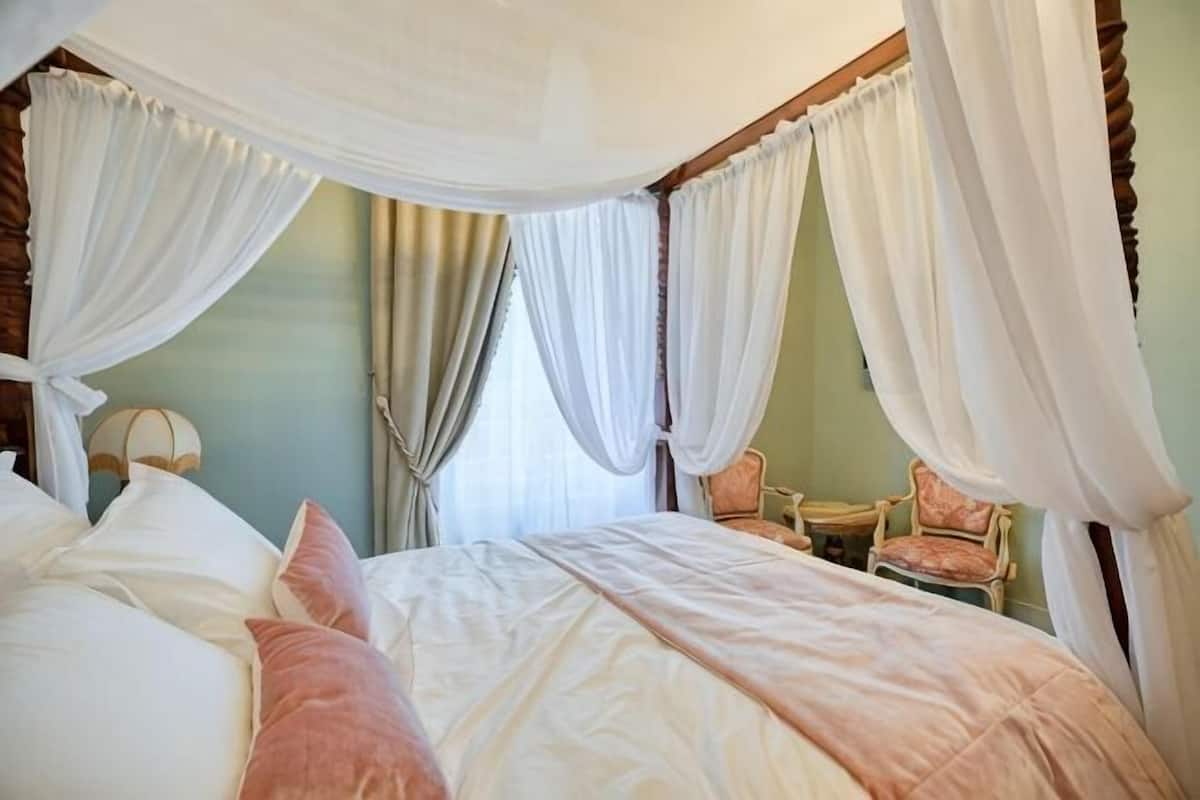 Une chambre à coucher avec un lit à baldaquin, une table de chevet, une chaise et une petite table.