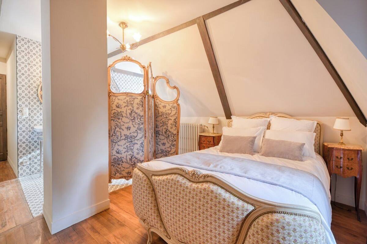 Une chambre à coucher avec un grand lit, une tête de lit décorative et un miroir ornemental.