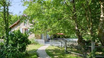 A stone house with a gravel path leading to a white picket fence.