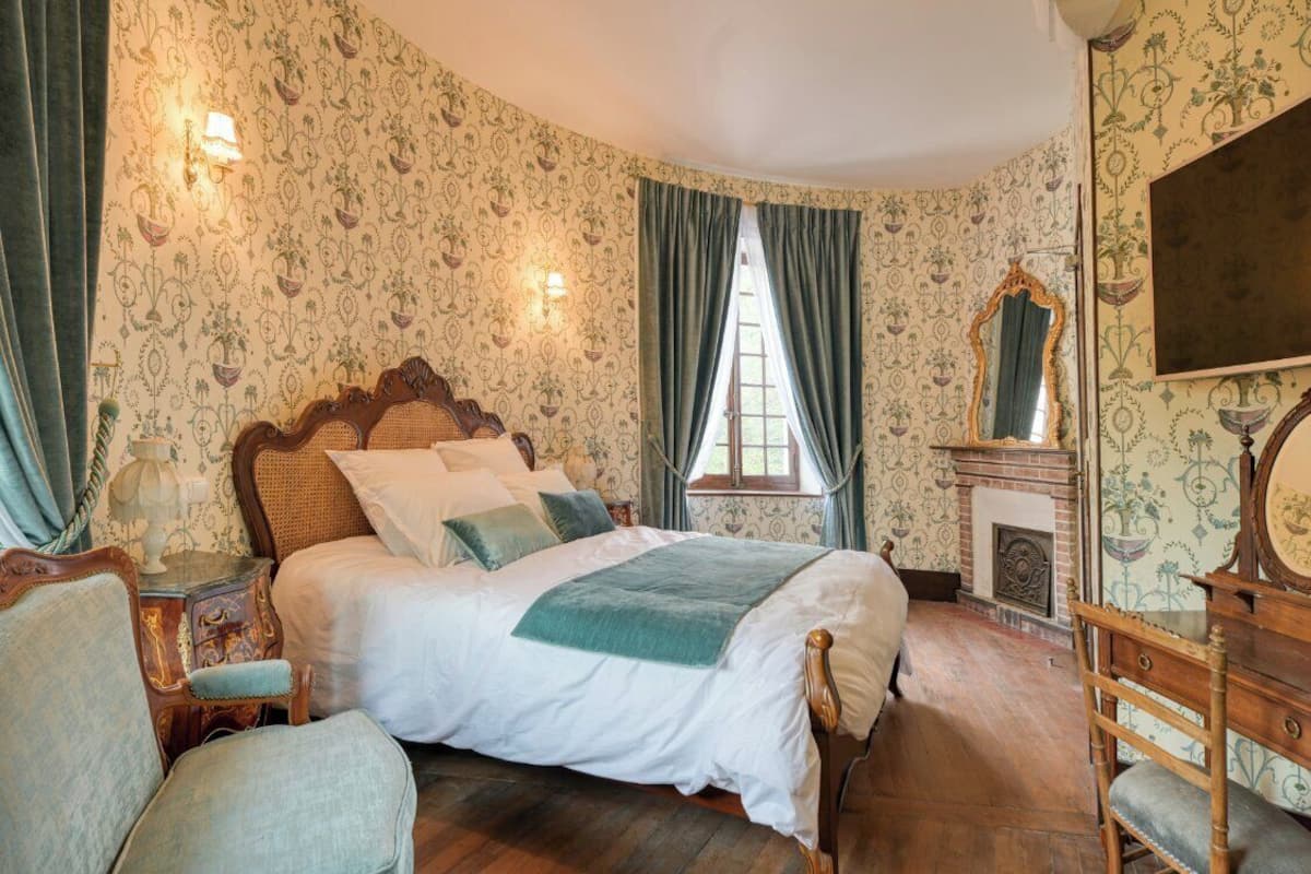 Une chambre à coucher de style traditionnel, avec un grand lit, une cheminée et un miroir.