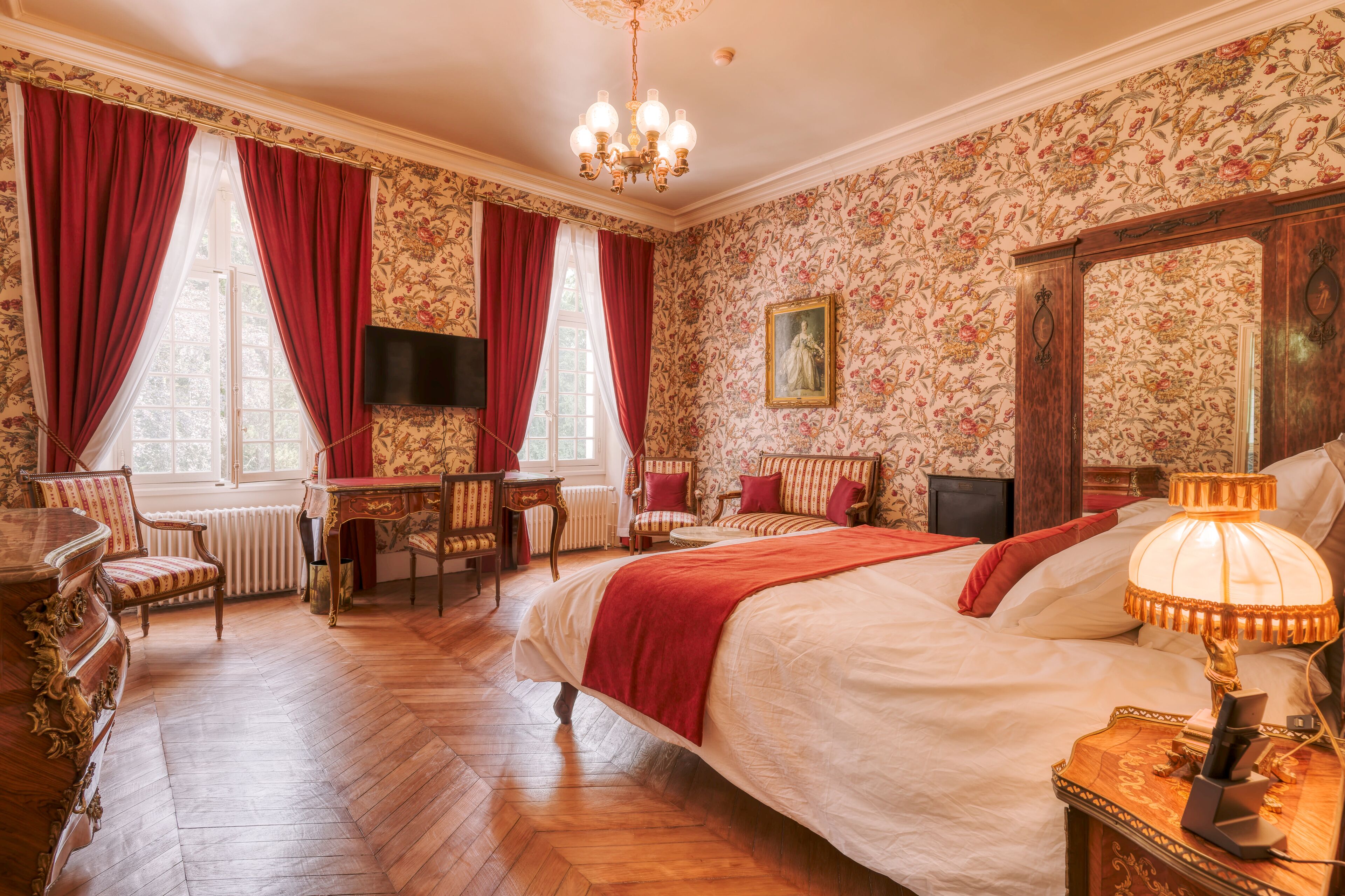 Una camera da letto con un letto grande, una scrivania, sedie, una televisione e uno specchio.