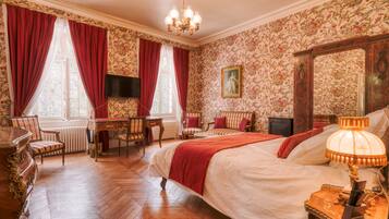Una camera da letto con un letto grande, una scrivania, sedie, una televisione e uno specchio.