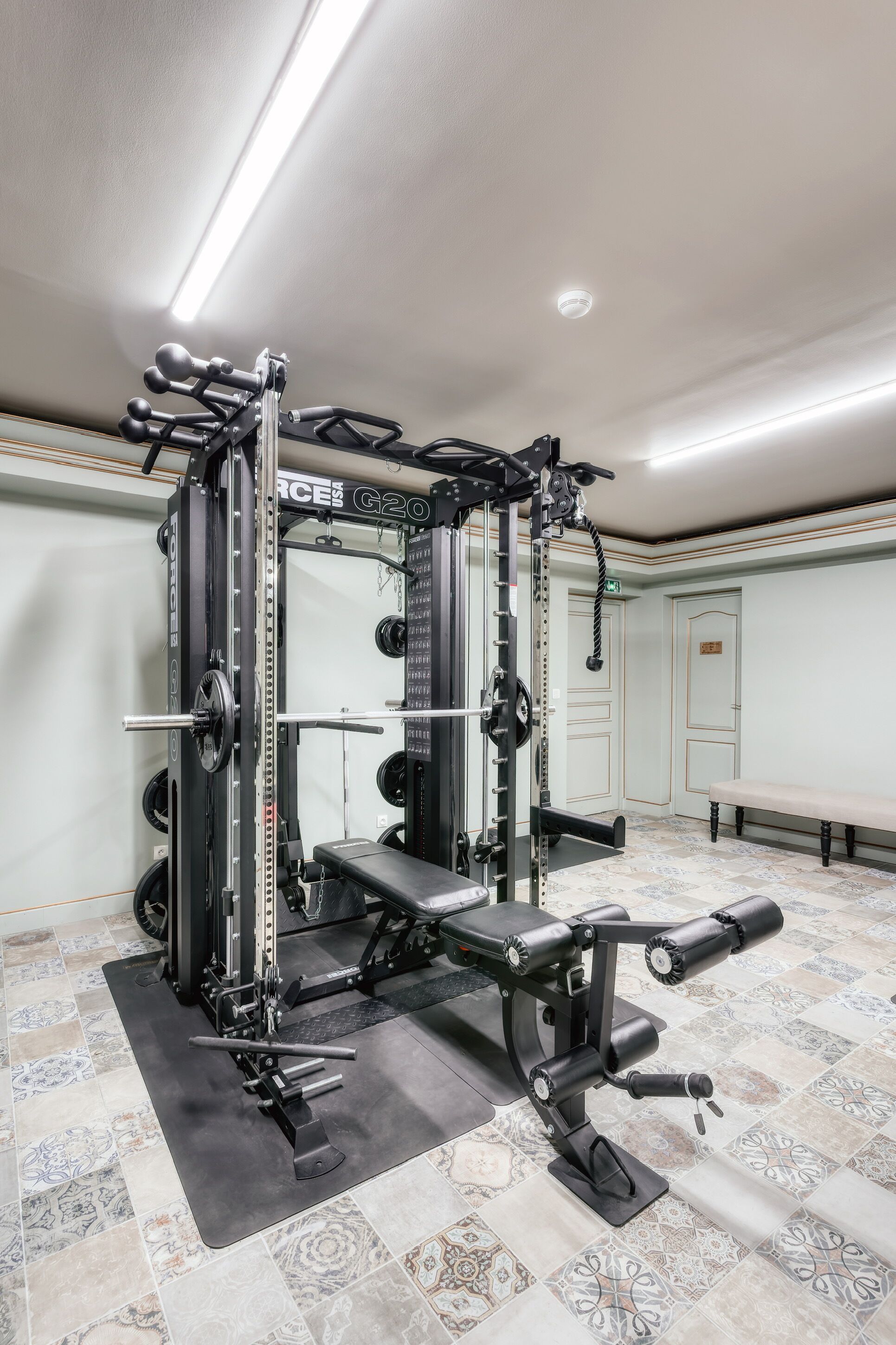Ein Fitnessraum mit Squat-Rack, Langhantelbank und verschiedenen Gewichtsplatten.