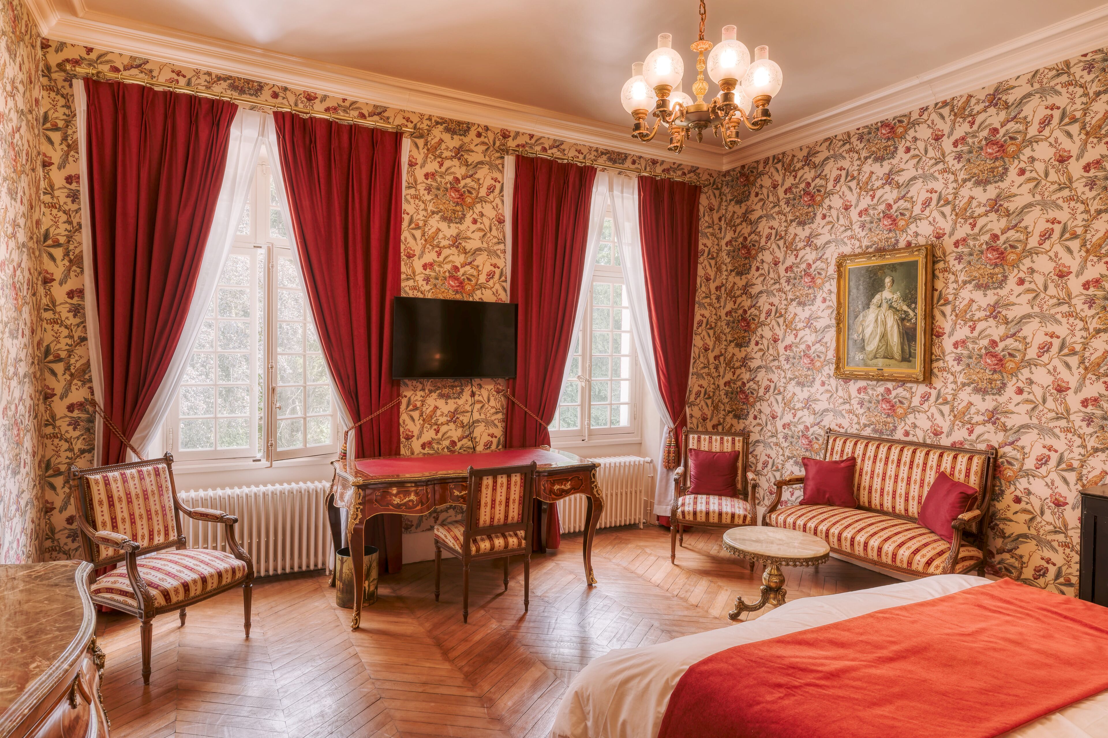 Um quarto com piso de madeira, mesa de jantar, cadeiras, sofá, televisão e radiador.