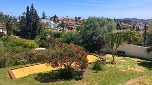 Ein Wohngebiet mit einem Garten, der einen Sandkasten, einen Kaktus und blühende Pflanzen zeigt.
